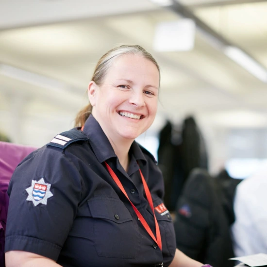 A London Fire Brigade member smiling at the camera from her desk.  
